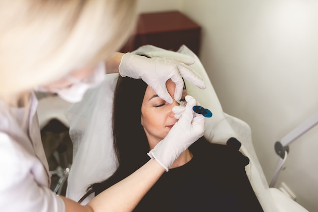 La donna fa l'iniezione di bellezza nel naso.