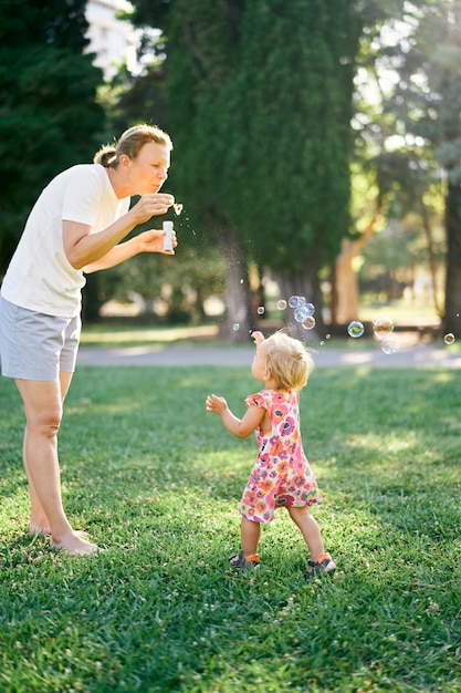 La donna fa le bolle di sapone e la bambina le prende