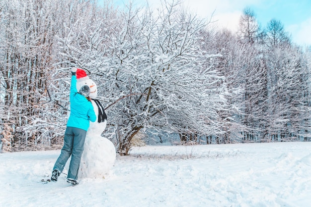 La donna fa un pupazzo di neve nel concetto di giornata invernale gelida