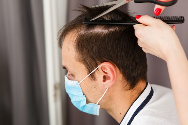 la donna fa un taglio di capelli a un uomo a casa durante la quarantena