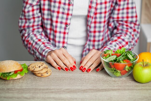 La donna fa una scelta tra cibi dannosi e sani.