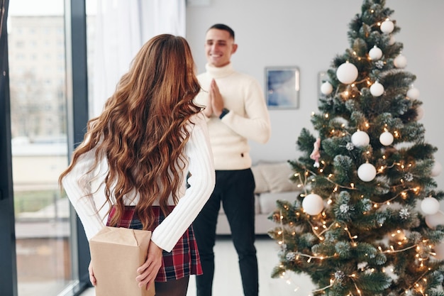 La donna fa una sorpresa per l'uomo La giovane coppia romantica festeggia insieme il nuovo anno al chiuso