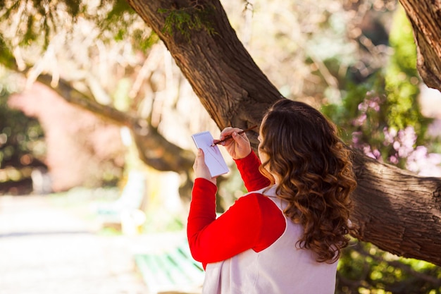 La donna fa uno schizzo nel suo taccuino in un parco primaverile