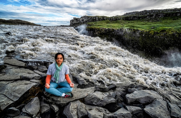 La donna fa yoga sulla caduta di Dettifoss in Islanda.