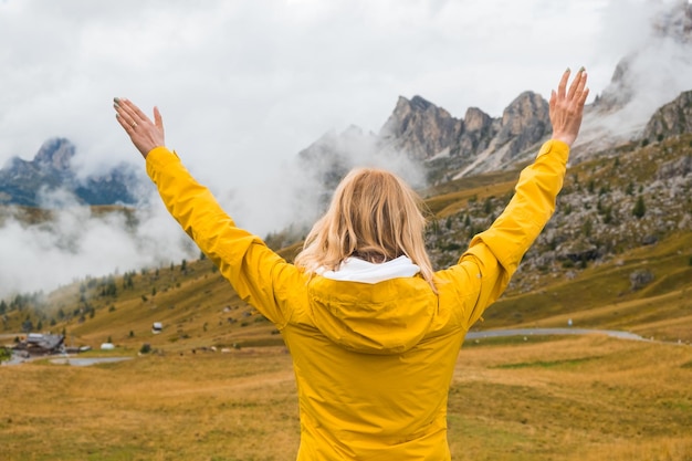 La donna felice allarga le mani e vede passare il Passo Giau in una fitta nebbia