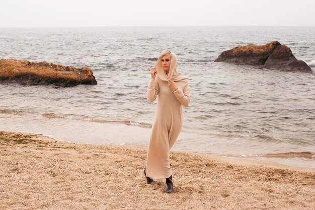 La donna felice ama guardare l'acqua mentre cammina sulla spiaggia vicino al mare