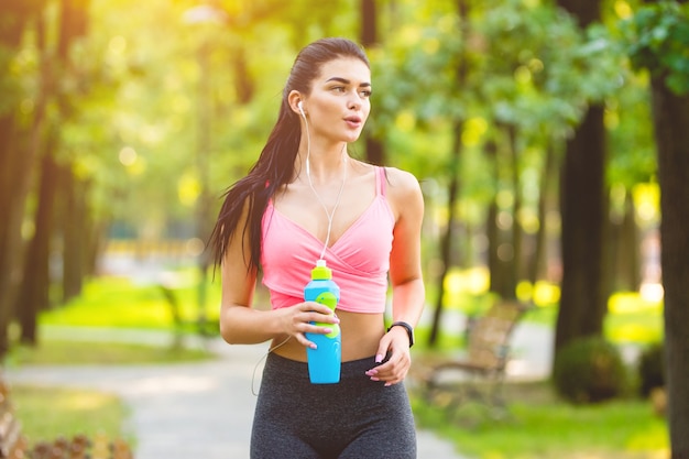 La donna felice che corre nel parco sullo sfondo soleggiato