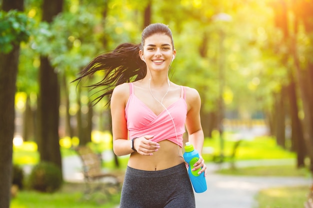 La donna felice che corre nel parco sullo sfondo soleggiato