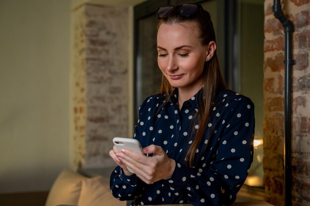 La donna felice emotiva guarda lo schermo dello smartphone legge un messaggio con notizie incredibili festeggia la ricezione di un premio per acquisti online o notifiche sulla vincita alla lotteria