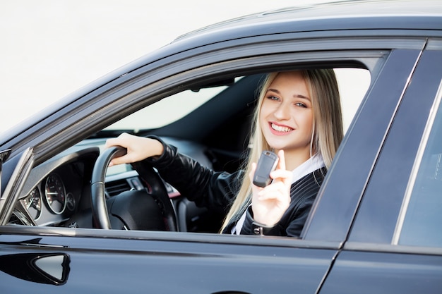 La donna felice gode di nuova automobile moderna acquistata