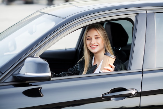 La donna felice gode di nuova automobile moderna acquistata