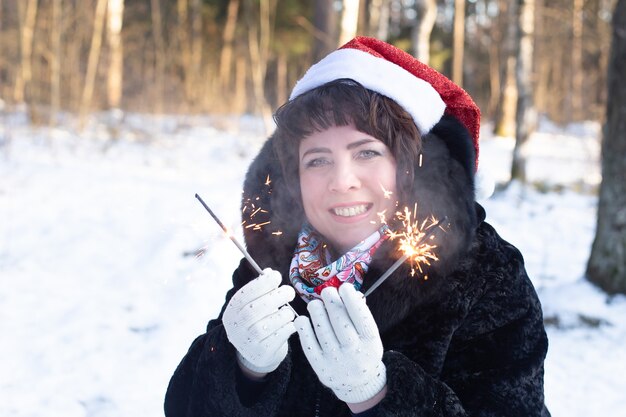 La donna felice in natura in inverno con le stelle filanti, Natale