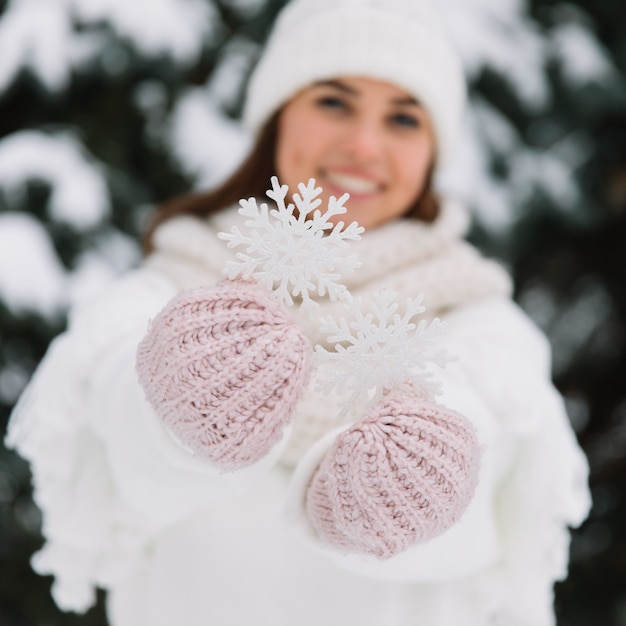 La donna felice in vestiti bianchi dell&#39;inverno che tengono un bello fiocco di neve in un parco.