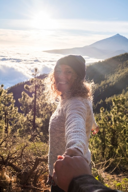 La donna felice sorride e si diverte all'aperto con il suo ragazzo insieme in montagna - pov di tenersi per mano e amare le coppie che si godono il tempo durante le vacanze di viaggio o il fine settimana