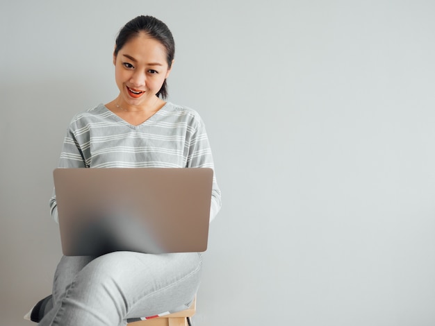 La donna felice sta usando un computer portatile per l&#39;affare.