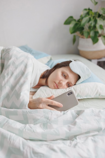 La donna giace a letto e sbadiglia o dorme con una maschera per dormire sul viso una donna europea con il sonno