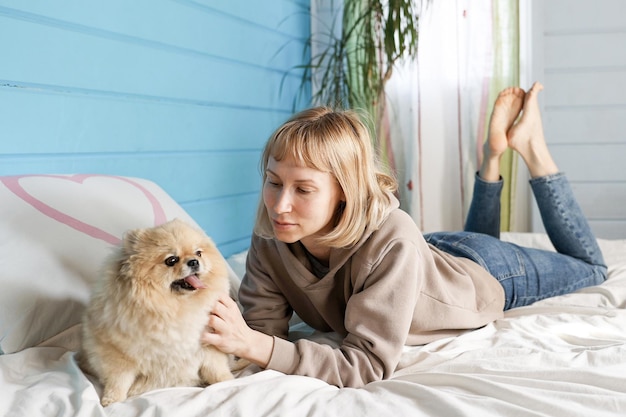 La donna gioca con il cane sul letto in camera da letto