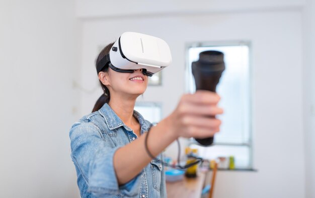 La donna gioca con il dispositivo di realtà virtuale e il joystick a casa