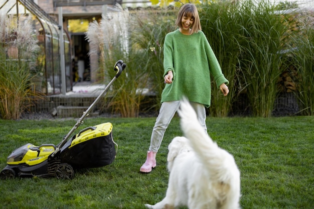 La donna gioca con il suo cane in cortile mentre fa giardinaggio
