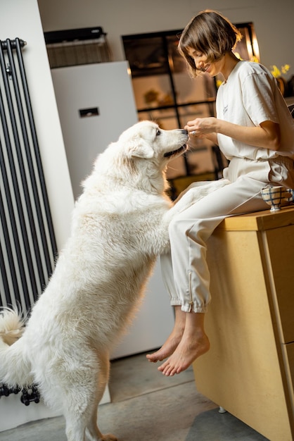 La donna gioca con il suo cane in cucina a casa