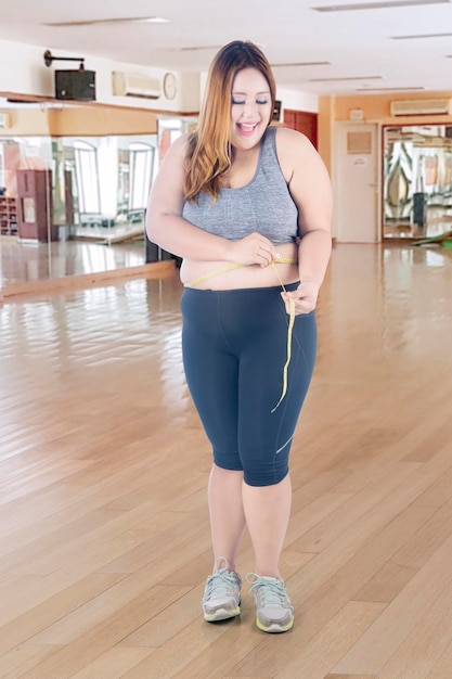 La donna grassa misura la sua vita nel centro fitness