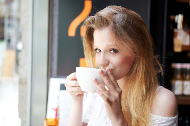 La donna graziosa beve una tazza di caffè