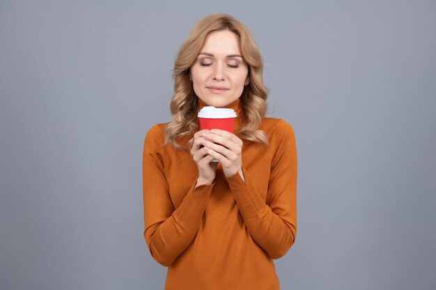 La donna graziosa con gli occhi chiusi gode dell'aroma del tè preparato fresco o del fondo grigio del caffè, godendosi la vita.