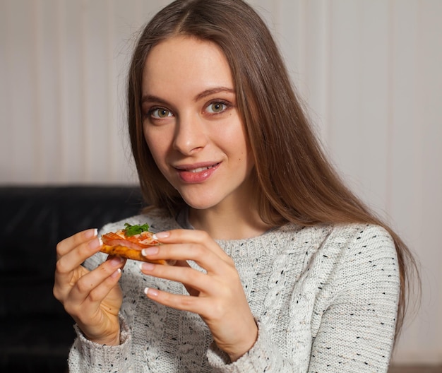 La donna graziosa sta tenendo una fetta di pizza nelle sue mani