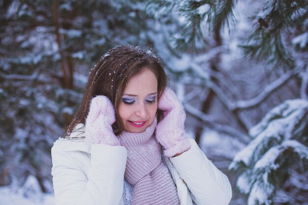 La donna guarda in basso e miglia sotto il pino innevato Neve sulle ciglia