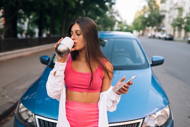 La donna guida l'auto ferma la pausa caffè usa lo smartphone