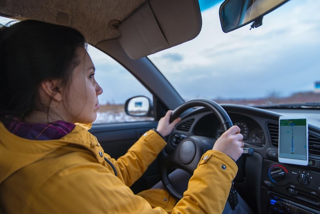 La donna guida l'auto nelle giornate invernali usa il telefono per la navigazione