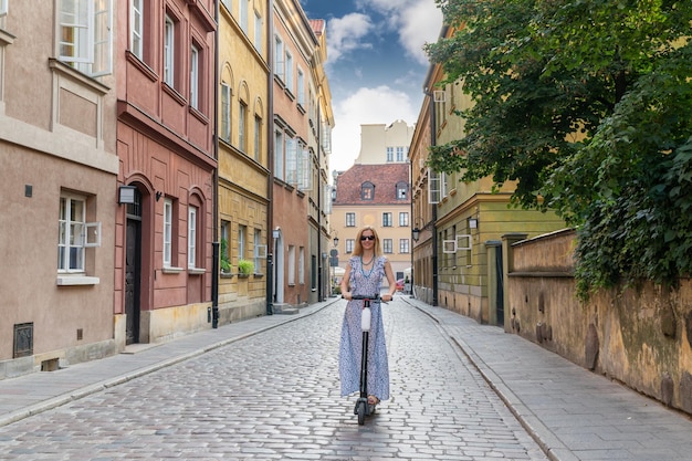 La donna guida uno scooter elettrico lungo la strada della città vecchia