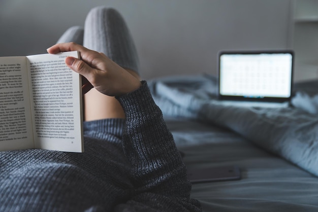 La donna ha letto il libro a letto. portatile sullo sfondo. studiare a letto