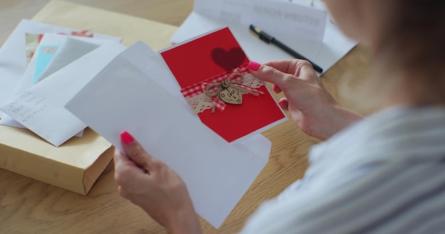 La donna ha ricevuto una lettera con un biglietto di auguri Closeup le mani della donna tirano fuori l'enveloppa del biglietto