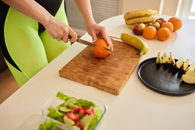 La donna ha tagliato l'arancia per mescolare succhi di frutta e verdura sani nel frullatore in cucina