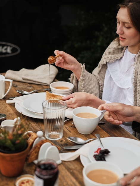 la donna impone il pane al miele, usando i cucchiai per miele specifico. colazione in natura