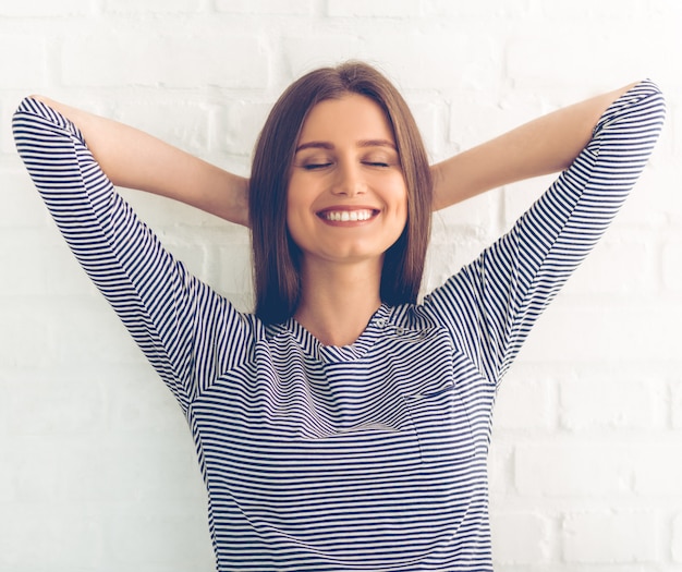 La donna in abbigliamento casual sta tenendo le mani dietro la testa.