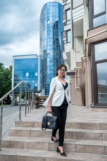 La donna in abiti da lavoro va in ufficio con la cartella con i documenti su un grande edificio