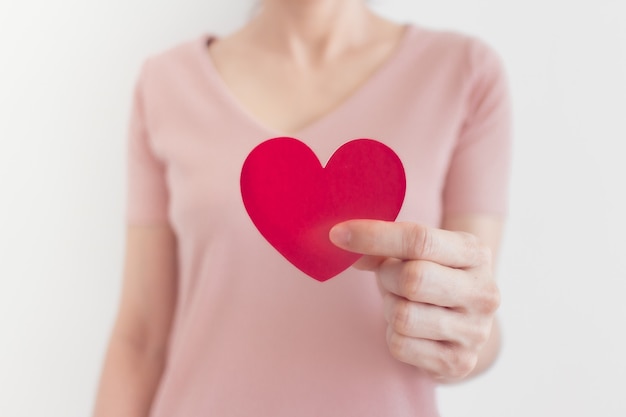 La donna in abito rosa mostra la forma del cuore nel concetto di amore e San Valentino.