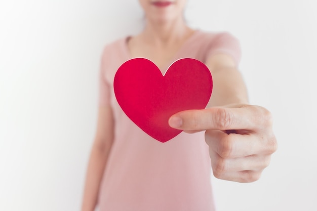 La donna in abito rosa mostra la forma del cuore nel concetto di amore e San Valentino.