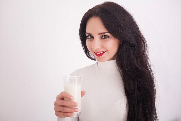 La donna in buona salute sveglia sta bevendo il latte da un vetro isolato