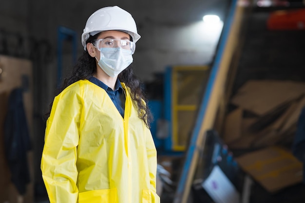 La donna in casco guarda i lavoratori che smistano i rifiuti nell'impianto