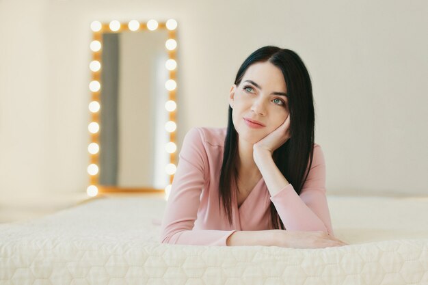 La donna in maglione rosa è sdraiata sul letto, pensando