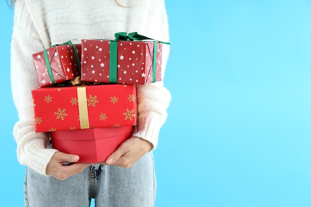 La donna in maglione tiene scatole regalo su sfondo blu