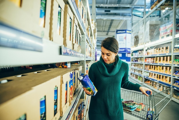 La donna in negozio ha letto gli ingredienti del succo. fare la spesa. copia spazio