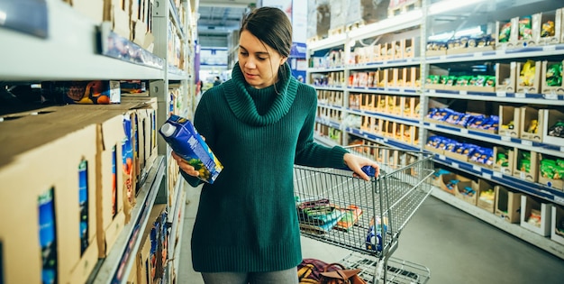 La donna in negozio ha letto gli ingredienti del succo. fare la spesa. copia spazio