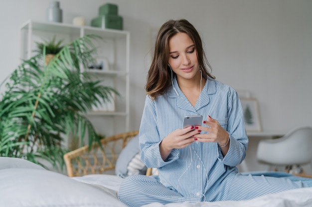 La donna in pigiama gode di playlist audio, ascolta musica canzoni romantiche in cuffia