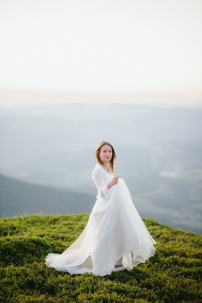 La donna in un abito da sposa corre attraverso il campo verso le montagne