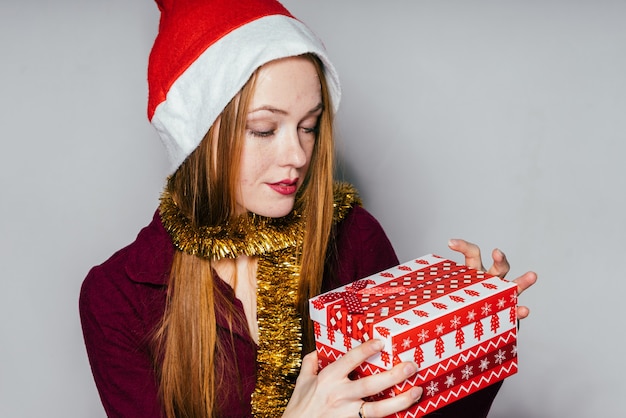 La donna in un cappello di Capodanno tiene un regalo nelle sue mani