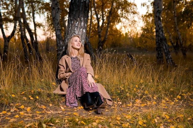 La donna in un lungo cappotto nella foresta di autunno